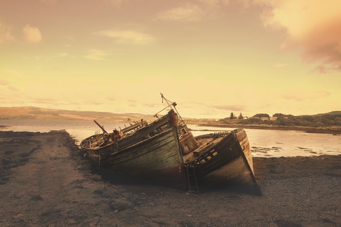 Abandoned Wooden Shipwreck on Rocky Shore at Sunset