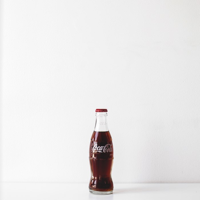 A glass bottle of Coca-Cola on a white surface
