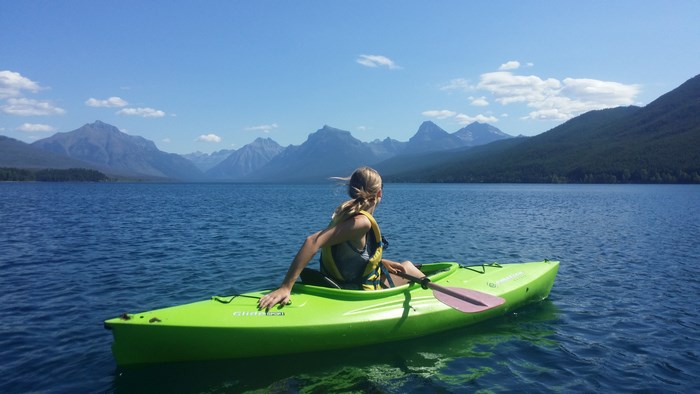 Woman kayaking on a lake with mountains