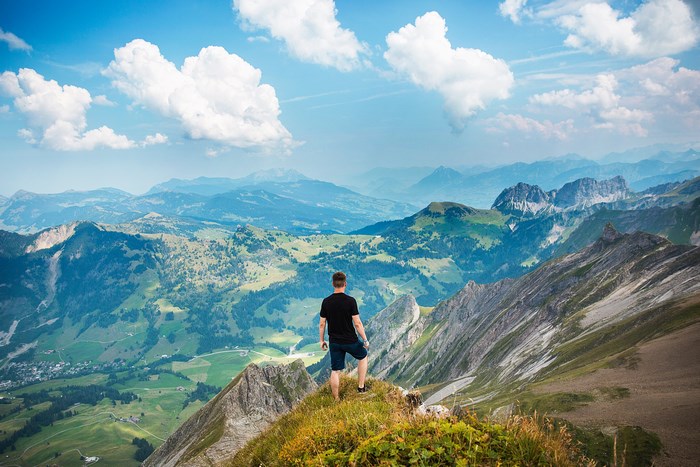 Man on a mountain peak overlooking a valley