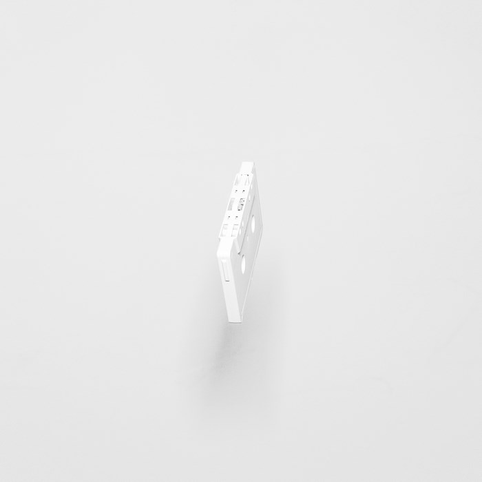White cassette tape levitating on a light grey background