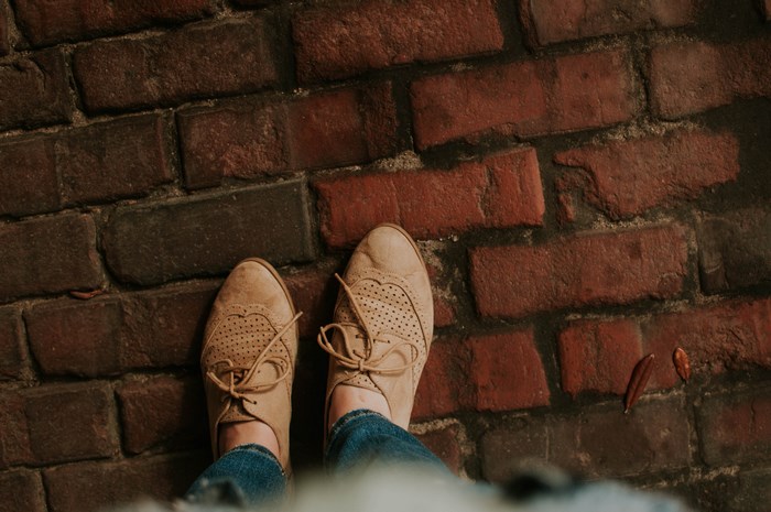 Brown shoes and denim jeans on a brick background