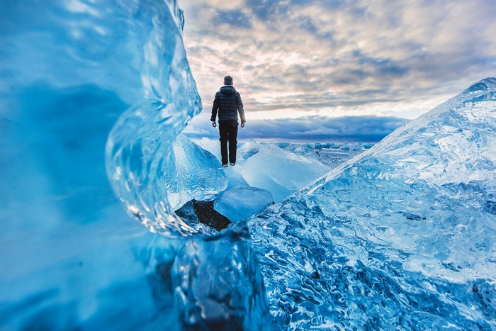 Man standing on icebergs with cloudy sky