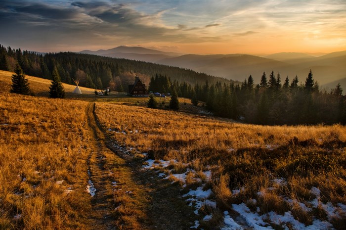 Mountain landscape with a cabin and tipi at sunset