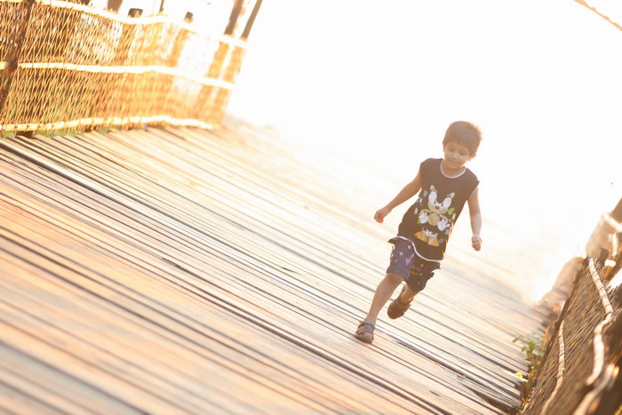 Boy running on a wooden bridge with a Mickey Mouse t-shirt