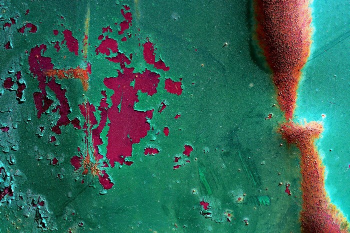 Abstract macro of peeling green paint and rust on metal