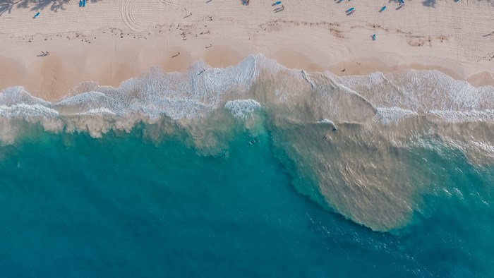 Aerial view of a tropical beach with turquoise water and waves