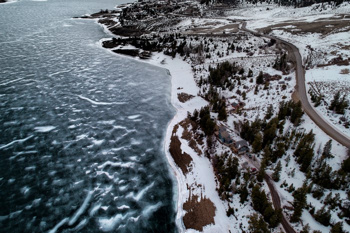 Aerial view of a frozen coastline with a road and houses
