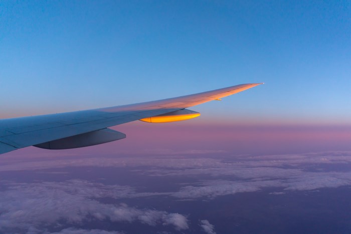 Airplane wing at sunset over clouds