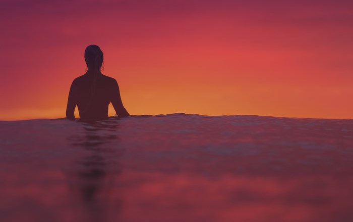Silhouette of a person in the ocean at sunset