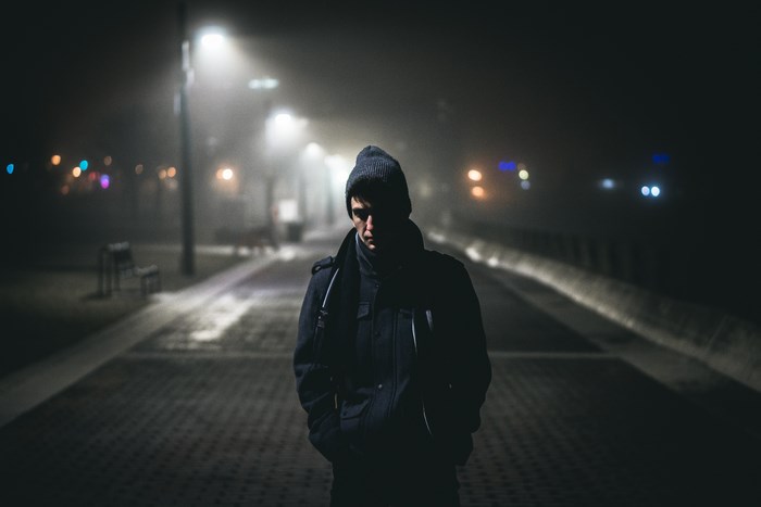 Man in beanie and coat on a foggy night street