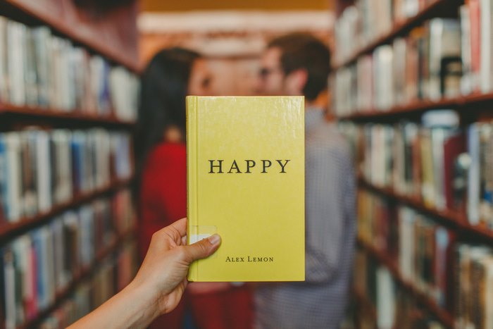 Happy book held by a hand in a library