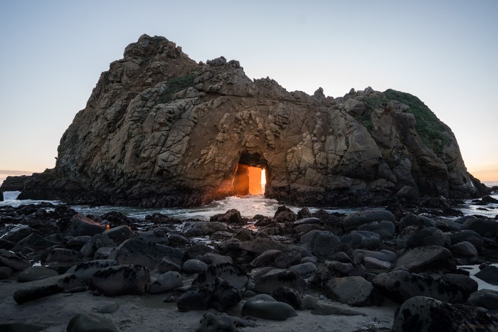 Rock formation with a natural archway at sunset