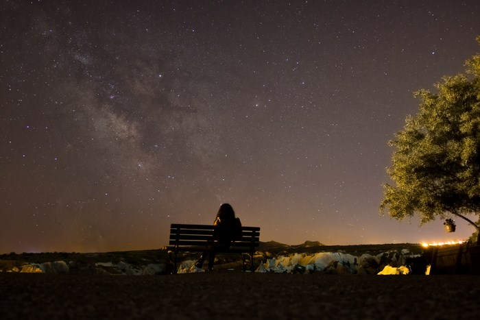 Person sitting on a bench under the Milky Way