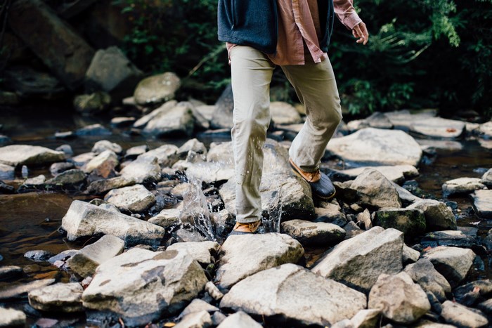 Person crossing a rocky stream in a forest