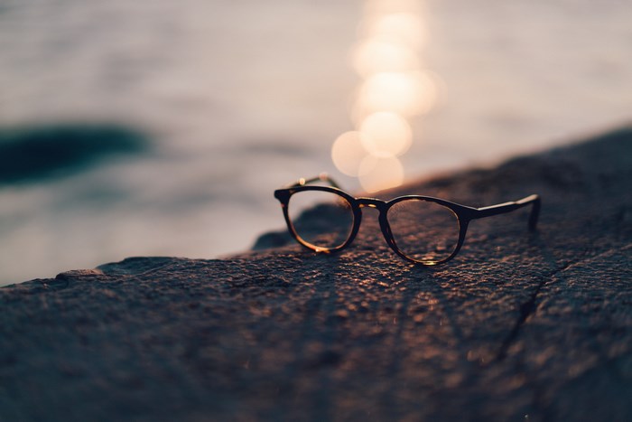 Eyeglasses on a rock by the water at sunset
