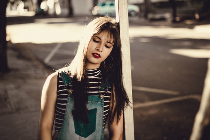 Woman leaning against a post in the city