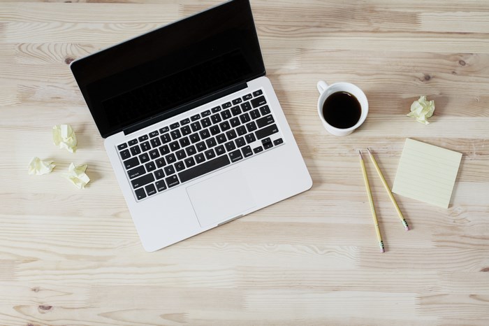 Apple laptop with coffee and notepad on wooden desk