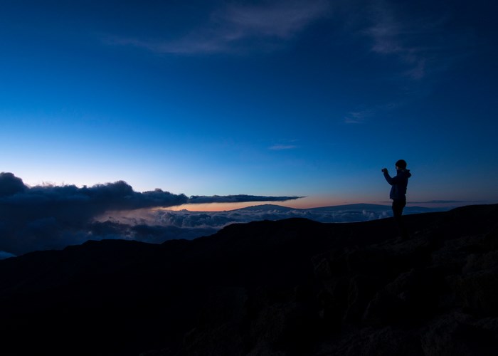 Silhouette of a person photographing clouds at sunrise