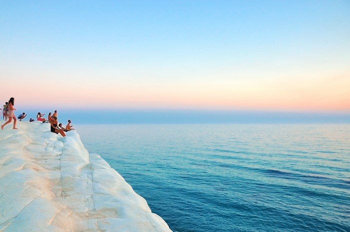 People on white cliff overlooking the sea at sunset