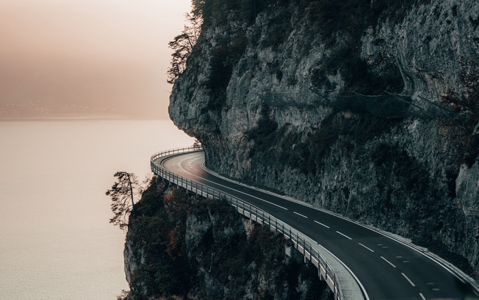 Road carved into a cliff overlooking a body of water