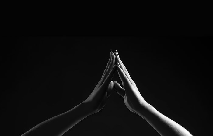 Two hands forming a triangle against a black background