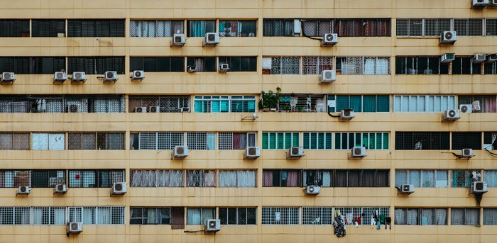 Apartment building facade with many windows and air conditioners