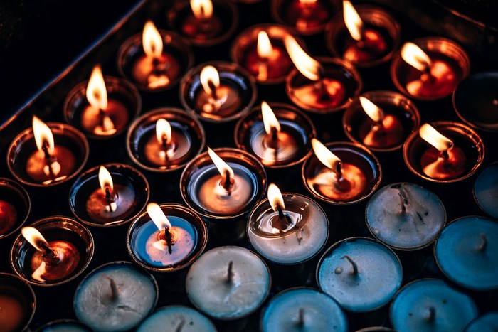 Many lit candles in small metal cups