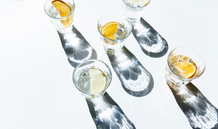Glasses of water with citrus slices and shadows