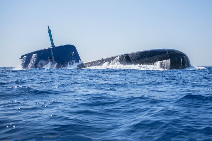Blue submarine surfacing in the ocean