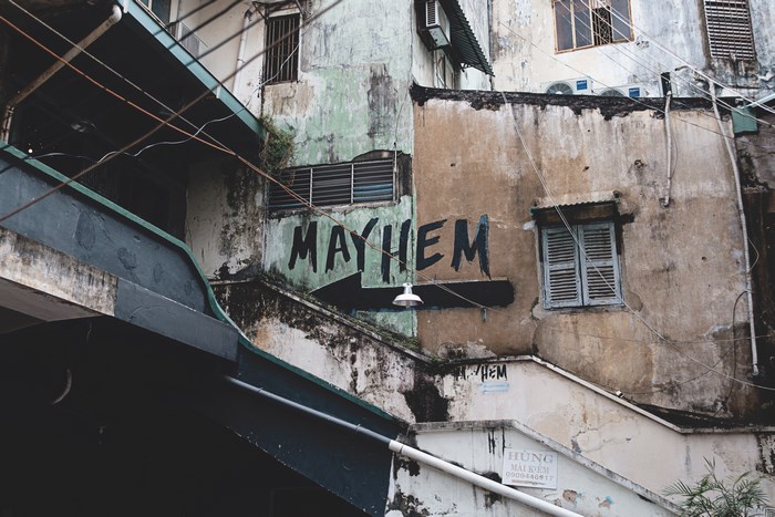 Graffiti art spelling "MAYHEM" on a weathered building exterior