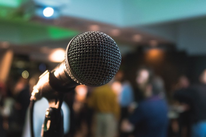 Close-up of a microphone on a stand with a blurred crowd