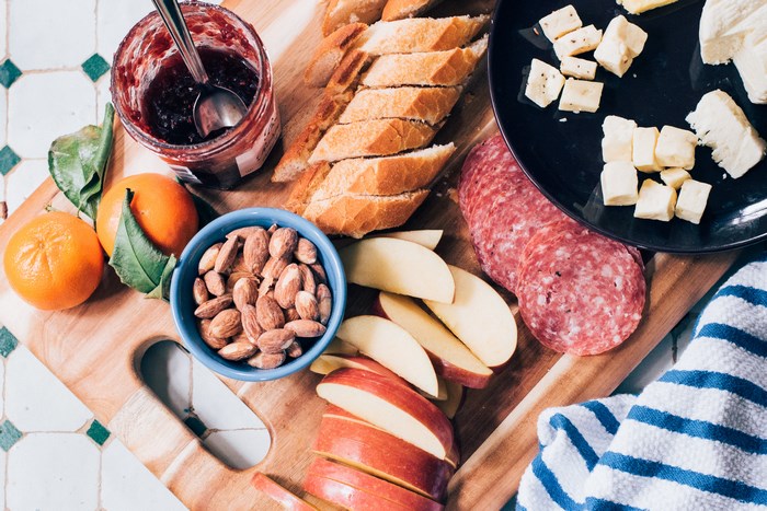 Charcuterie board with salami, cheese, fruit, nuts, and jam