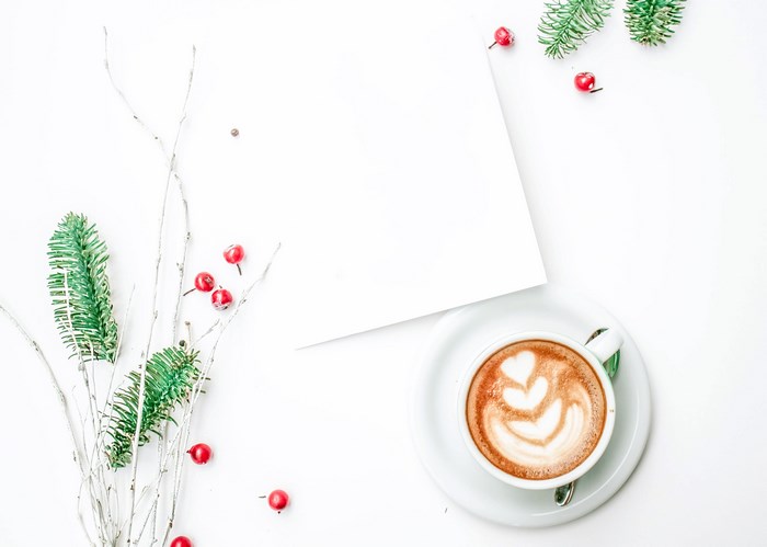Flatlay of Christmas branch, berries, and cappuccino