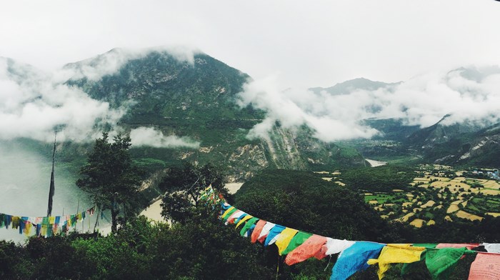 Colorful prayer flags in a cloudy mountain valley landscape