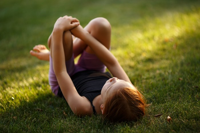 Girl lying on grass holding her knees