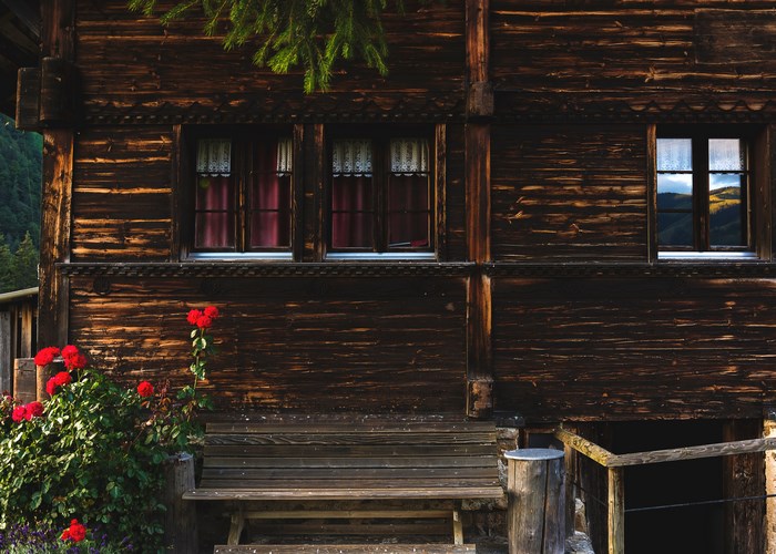 Wooden chalet with red roses and a bench in Switzerland