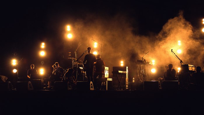 Scalene band performing live music on stage with orange lights