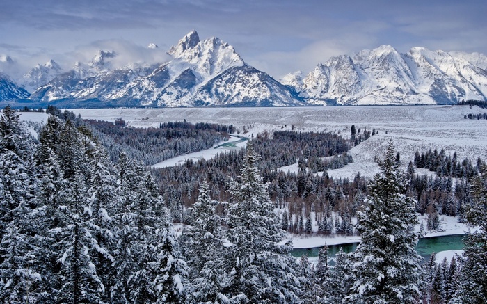 Snow-covered mountains and forest with a river