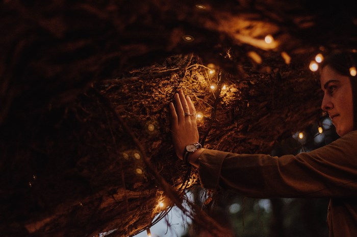 Woman touching fairy lights in a dark structure