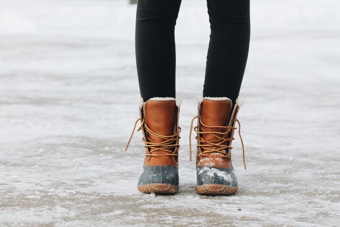 Woman wearing brown and grey winter boots in snow
