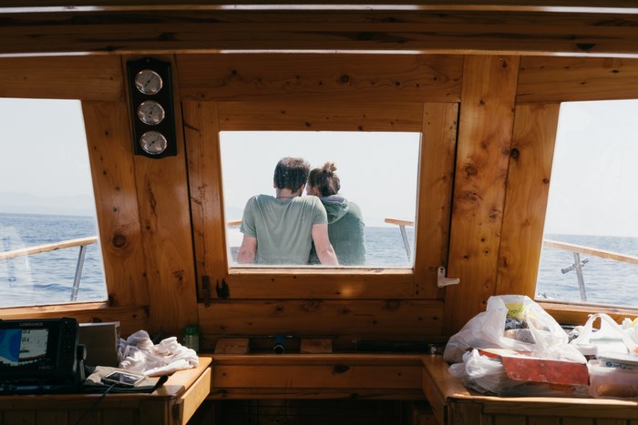 Couple in a boat cabin looking out at sea