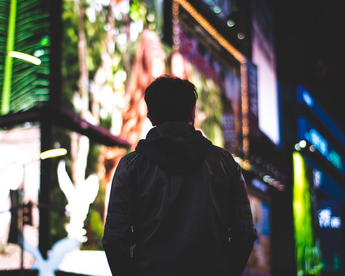 Man in Hoodie Looking at Bright City Lights at Night