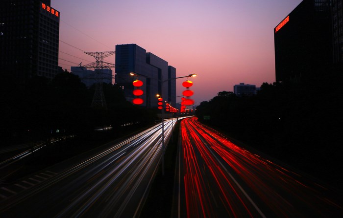 City street with red lanterns and light trails at sunset