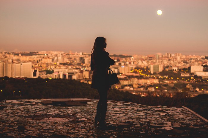 Silhouette of a woman overlooking Lisbon at sunset