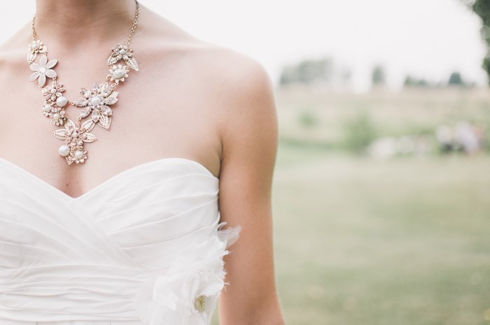 Bride wearing a floral pearl necklace and white gown
