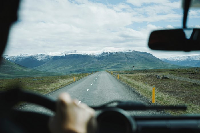 Driving on a road towards snow-capped mountains
