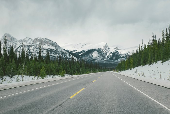 Road through snowy mountains and forest in Jasper, Canada