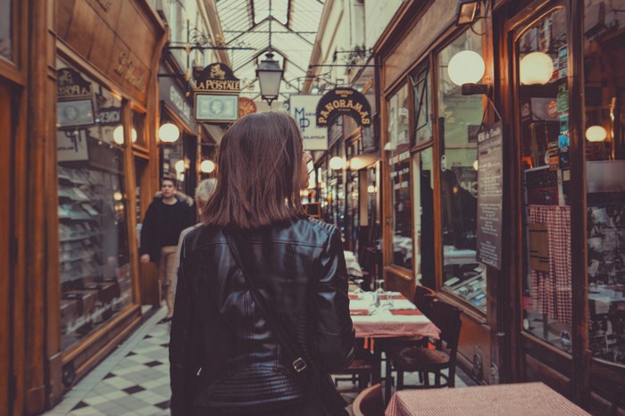Woman walks through a Parisian passage with shops and cafes