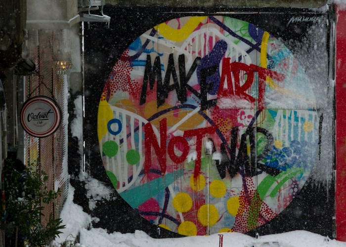 Graffiti mural 'Make Art Not War' on a wall in the snow